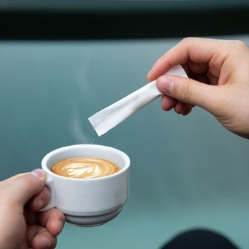 Man pouring sugar to the latte coffee