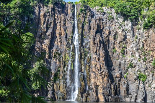 Rockface with waterfall Cascade Niagara at french island Reunion in the indian ocean on a sunny day with blue sky