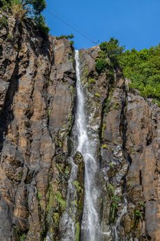 Rockface with waterfall Cascade Niagara at french island Reunion in the indian ocean on a sunny day with blue sky
