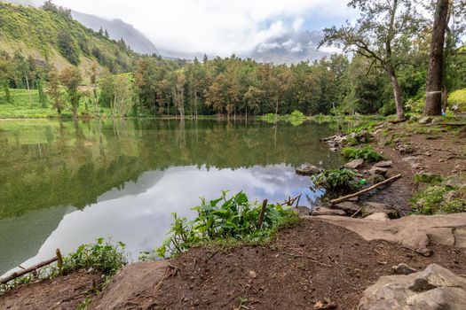 Landscape with idyllic lake, mountain range, green trees in the interior of the island Reunion in the indian ocean 