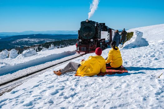 couple men and woman hiking in the Harz national park Germany, Steam train on the way to Brocken through the winter landscape, Famous steam train through the winter mountain. Brocken, Harz Germany