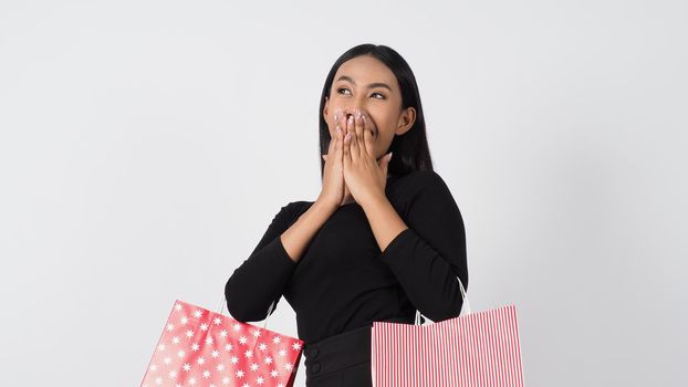 Sexy woman shopping. Portrait of excited beautiful girl wearing black holding red shopping bags isolated over white background. Cheerful happy lady enjoy carrying goods bags. half body.