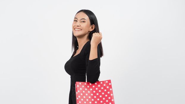 Sexy woman shopping. Portrait of excited beautiful girl wearing black holding red shopping bags isolated over white background. Cheerful happy lady enjoy carrying goods bags. half body.