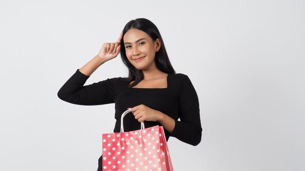 Sexy woman shopping. Portrait of excited beautiful girl wearing black holding red shopping bags isolated over white background. Cheerful happy lady enjoy carrying goods bags. half body.