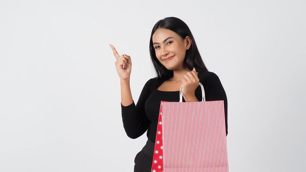 Sexy woman shopping. Portrait of excited beautiful girl wearing black holding red shopping bags isolated over white background. Cheerful happy lady enjoy carrying goods bags. half body.