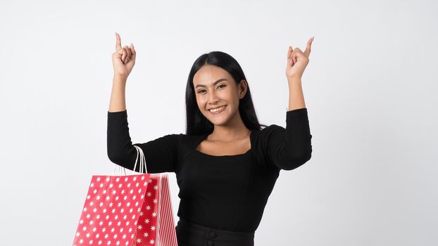 Sexy woman shopping. Portrait of excited beautiful girl wearing black holding red shopping bags isolated over white background. Cheerful happy lady enjoy carrying goods bags. half body.