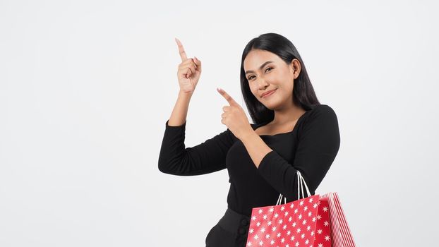 Sexy woman shopping. Portrait of excited beautiful girl wearing black holding red shopping bags isolated over white background. Cheerful happy lady enjoy carrying goods bags. half body.