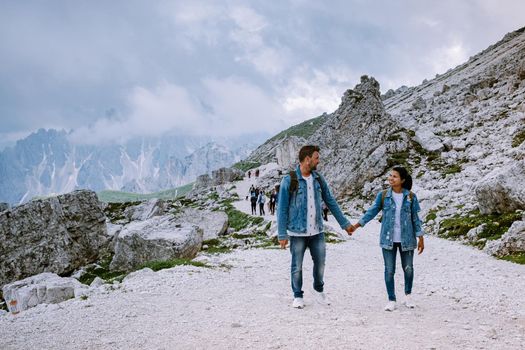 couple hiking in the italian dolomites during foggy weather with clouds, Stunning view to Tre Cime peaks in Dolomites, Italy. Europe