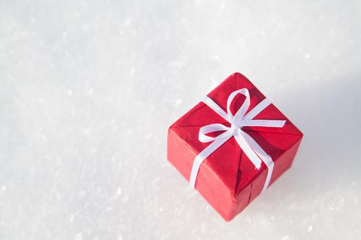 Small Christmas gift box on white snow background with copy space