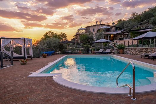 Luxury country house with swimming pool in Italy. Pool and old farm house during sunset central Italy