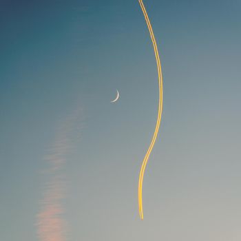 Jet airplane, its contrail and a crescent moon at sunset. The plane seems to go around the moon. Square crop.
