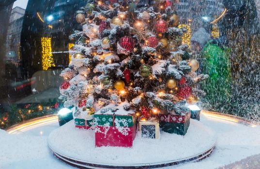 A Christmas tree with gifts underneath, covered with freshly fallen snow.