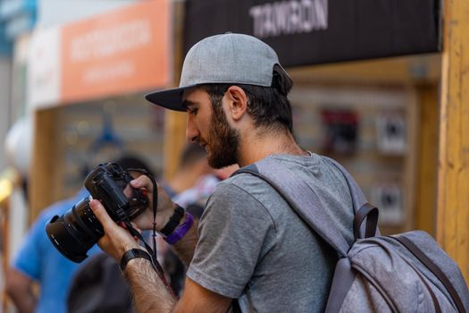 August 18, 2018. Moscow, Russia. A young man in a gray cap looks at the picture he has just taken on the screen of his DSLR.