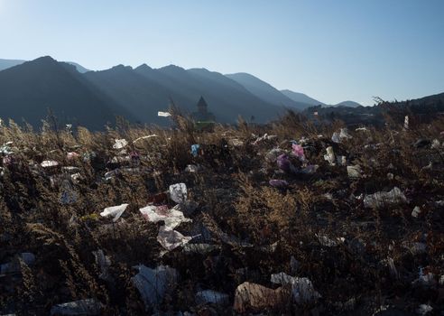 Plastic debris washed ashore by the flood, against the background of an old Georgian church.