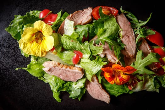 Vegetable salad with pork on a dark plate