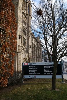 Ottawa, Ontario, Canada - November 18, 2020: The Connaught Building stands behind a sign for the National Headquarters of the Canada Revenue Agency (CRA) in Ottawa.