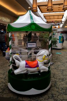 Ottawa, Ontario, Canada - December 11, 2020: A coin-operated carousel kiddie ride in Carlingwood Shopping Centre is wrapped in plastic as it is temporarily closed during the COVID-19 pandemic.