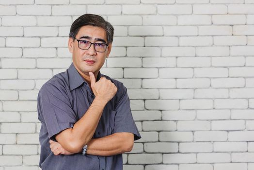 Portrait of Asian handsome senior elderly man wear eyeglasses on white brick wall background. Old man standing golden age grandfather healthcare cheerful lifestyle