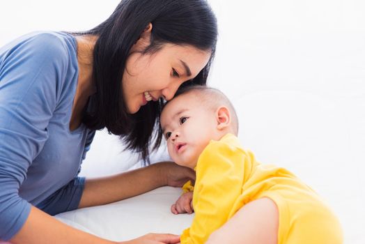 Portrait of beautiful young Asian mother kissing her infant newborn baby in a white bed, The mom loves his child, Healthcare and medical and mother day concept