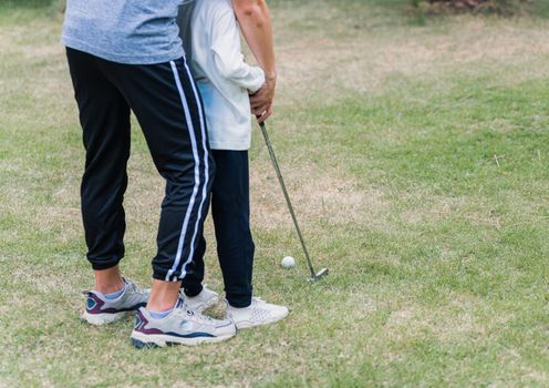 Asian young father support teaching training daughter to play perfect golf while standing in the game of golf together in nature a field garden park, family outdoors sport concept