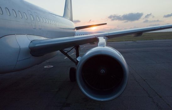 The wing and engine of the plane in the light of the setting sun