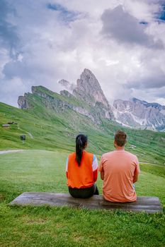 couple on vacation hiking in the Italien Dolomites, Amazing view on Seceda peak. Trentino Alto Adige, Dolomites Alps, South Tyrol, Italy, Europe. Odle mountain range, Val Gardena. Majestic Furchetta peak in morning sunlight. Italy