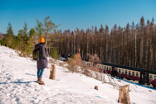 woman hiking in winter landscape Harz national park Germany, Steam train on the way to Brocken, Famous steam train through the winter mountain, Harz National Park Mountains in Germany Europe