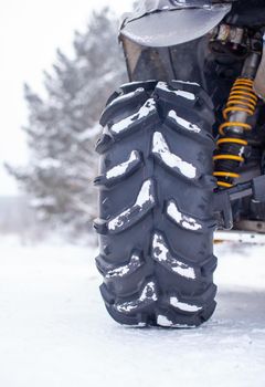 Close-up of a quad bike wheel and 4-wheel drive. ATV in the forest in winter. Riding a quad bike.