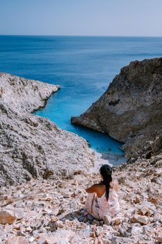 Crete Greece Seitan Limania beach with huge cliff by the blue ocean of the Island of Crete in Greece, Seitan limania beach on Crete, Greece. Europe young woman mid age asian looking out over ocean during vacation