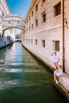 couple on a city trip in Venice, Loving couple on vacation in Venice, Italy Millennials sitting on a canal with gondolas. Europe