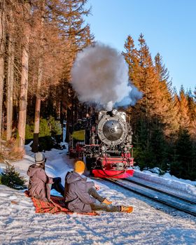 couple men and woman hiking in the Harz national park Germany, Steam train on the way to Brocken through the winter landscape, Famous steam train through the winter mountain. Brocken, Harz Germany