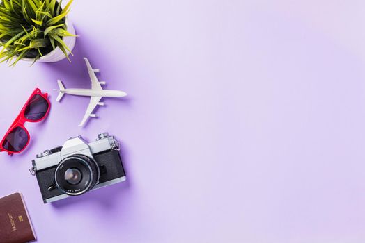 Top view flat lay mockup of retro camera films, airplane, sunglasses traveler accessories isolated on a purple background with copy space, Business trip, and vacation summer travel concept