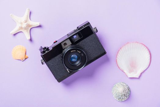 Top view flat lay mockup of camera films, shells, starfish beach traveler accessories on a purple background with copy space, Business trip, and vacation summer travel concept