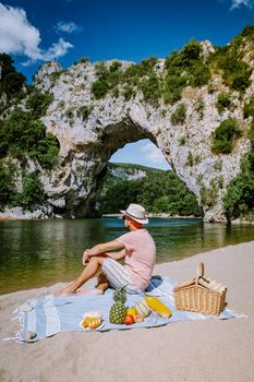 couple on the beach by the river in the Ardeche France Pont d Arc, Ardeche France,view of Narural arch in Vallon Pont D'arc in Ardeche canyon in France Europe