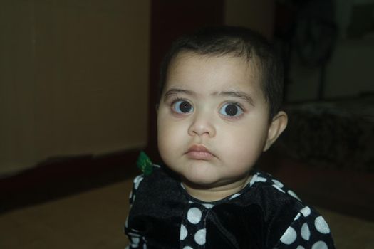 Baby girl with lovely face, big eyes and cute face gesture. Toddler baby making sweet activities