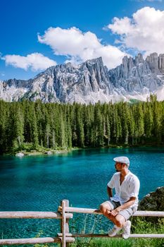 men visit hte bleu lake in the dolomites Italy, Carezza lake Lago di Carezza, Karersee with Mount Latemar, Bolzano province, South tyrol, Italy. Landscape of Lake Carezza or Karersee and Dolomites in background, Nova Levante, Bolzano, Italy. Europe