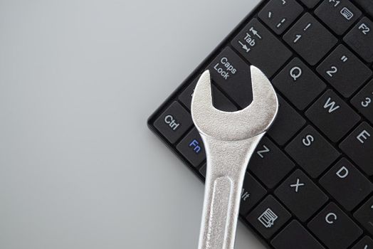Electronic technical support concept - spanner on computer keyboard