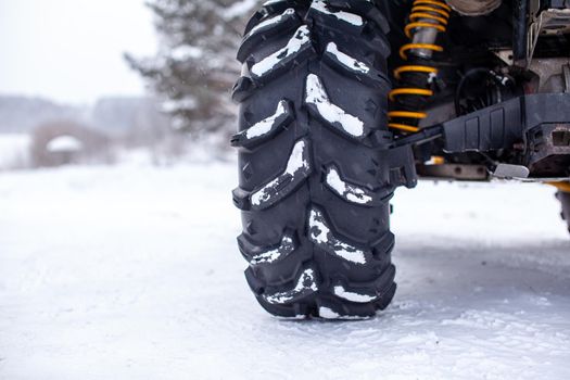 Close-up of a quad bike wheel and 4-wheel drive. ATV in the forest in winter. Riding a quad bike.