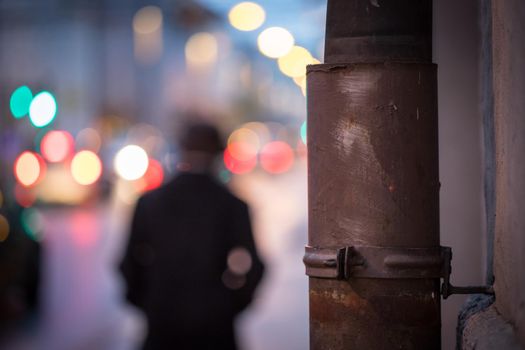 Closeup of rain drain, urban city lights in the blurry background