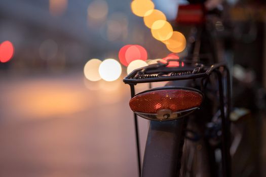 Rear picture of a city bike, blurry background with city lights, evening
