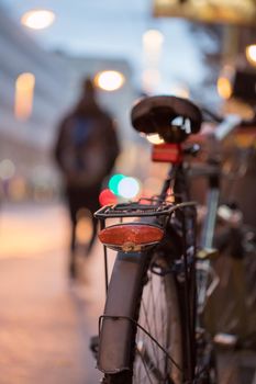 Rear picture of a city bike, blurry background with city lights, evening
