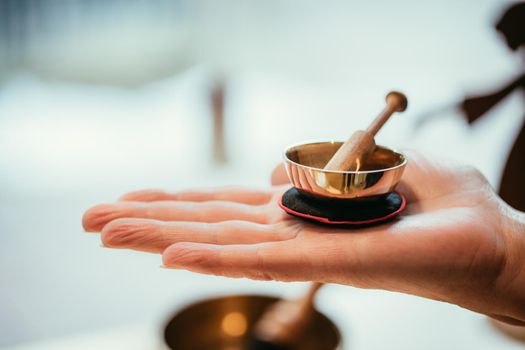 Small singing bowl holding in hand, blurry background
