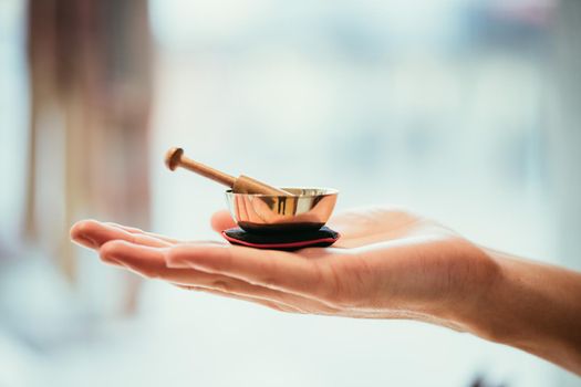 Small singing bowl holding in hand, blurry background