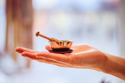 Small singing bowl holding in hand, blurry background