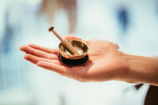 Small singing bowl holding in hand, blurry background