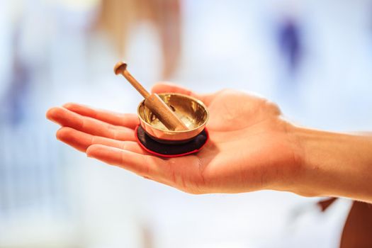 Small singing bowl holding in hand, blurry background