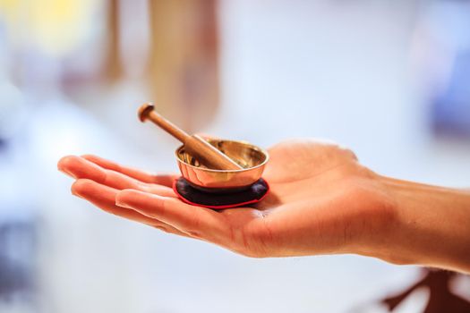 Small singing bowl holding in hand, blurry background