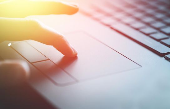 Close up picture of hands using a notebook touchpad, sunshine