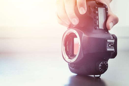 Hands of a photographer are touching a professional reflex camera, open sensor. Sunlight.
