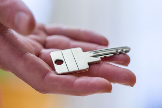 Holding a house key in the hand: New home and property.